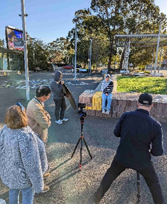 A group of people standing around a camera

Description automatically generated